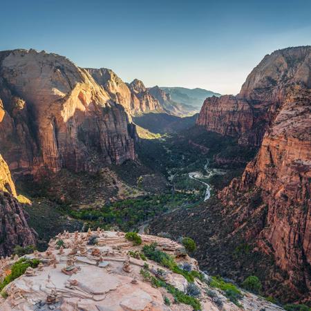a canyon with a river in the middle with Zion National Park in the background