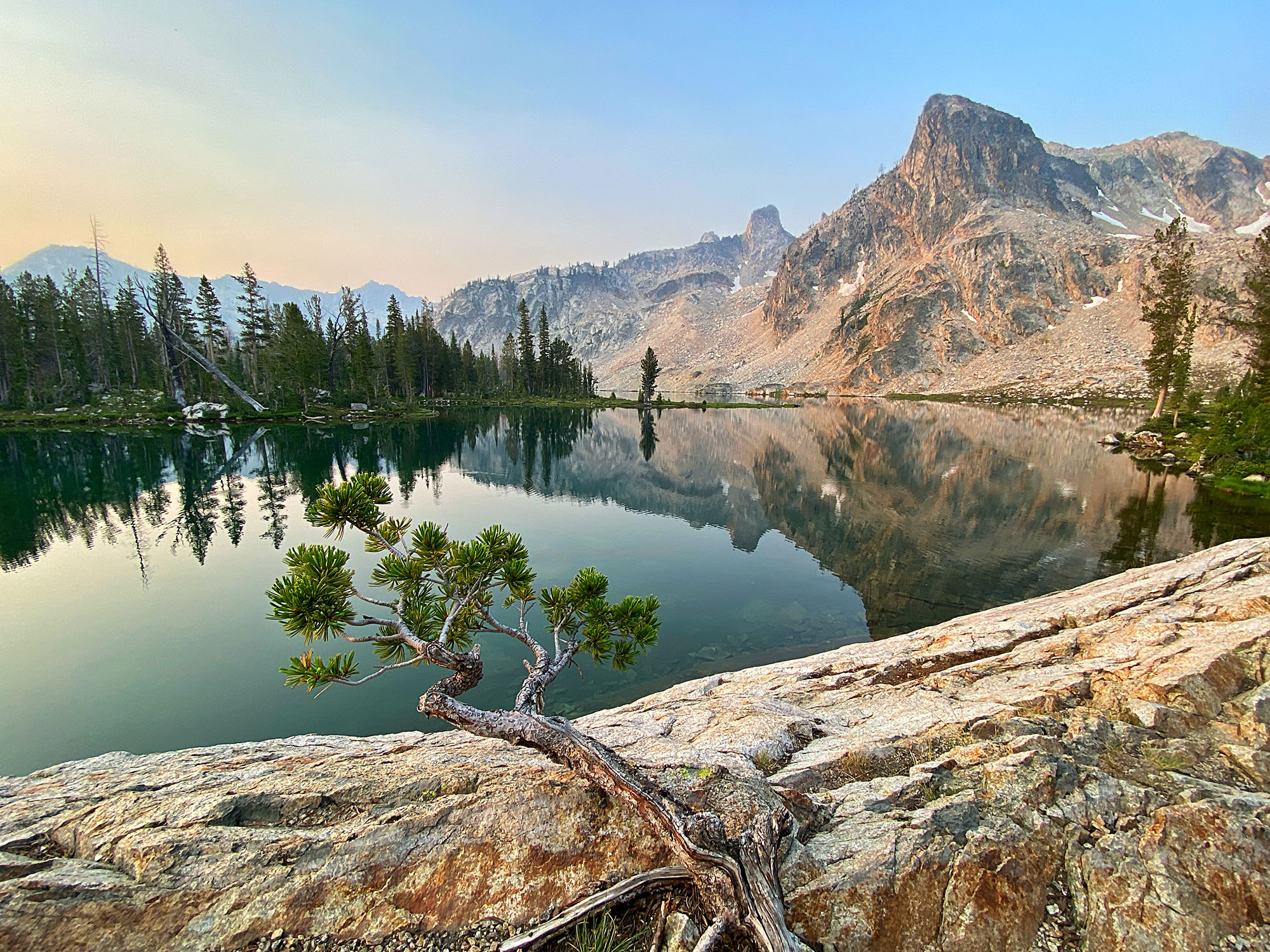 a lake with trees and mountains in the background